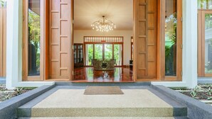 A traditional Japanese-style entrance with sliding doors, a central wooden table, and a chandelier.