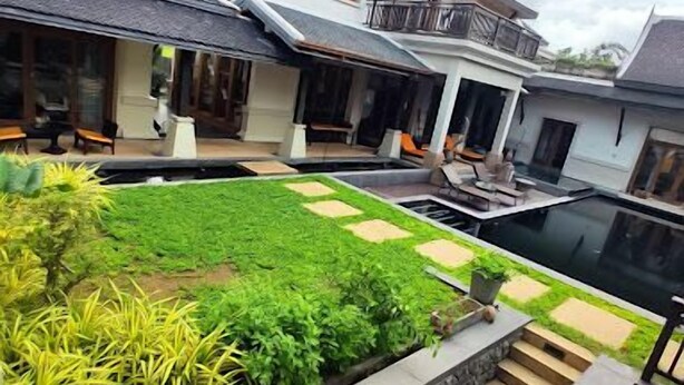 A modern house with a swimming pool, a well-maintained garden, and a staircase leading to a balcony.