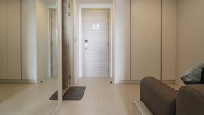 A modern interior with a hallway leading to a door, a sofa, and a bench. - Brand New 2 Bed Seaview Apartment Utopia Karon (karon)