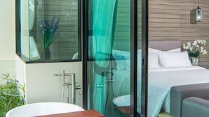 A modern hotel room with a glass shower enclosure, a bed with white linens, and a wooden headboard. - Brand New 2 Bed Seaview Apartment Utopia Karon (karon)