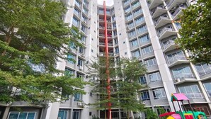 Een meerlaags woongebouw met balkons, een speeltuin en een hoge boom op de voorgrond.