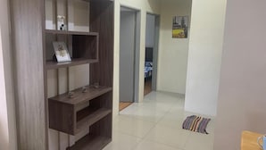 Een gang met een houten console tafel, een lijst met een afbeelding en een deur naar een andere kamer.