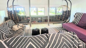 Una sala moderna con un sofá, un sillón a rayas y dos sillas colgantes.