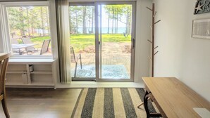 Una habitación con un amplio ventanal corredero que da a un patio exterior con vistas a árboles y un cuerpo de agua.