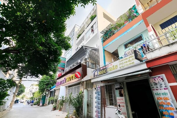 Une vue de rue avec un hôtel appelé « NHAI HOTEL » et un magasin dont l’enseigne est écrite dans une langue étrangère.