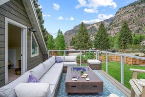 Un balcon avec un canapé, une table basse et une vue sur les montagnes.