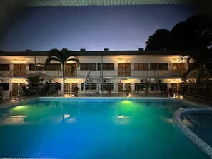 A hotel with a swimming pool, outdoor seating, and a staircase leading to the upper level.