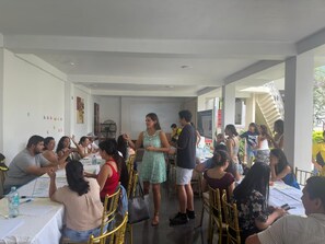 A conference room with tables arranged for a meeting, a whiteboard, and a person standing addressing the attendees. - CASA BLANCA HOTEL (Iquitos)
