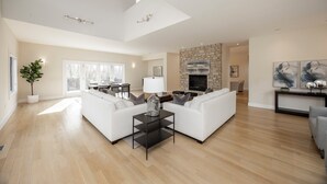 A spacious living room with a high ceiling, a stone fireplace, and a modern fireplace mantel.