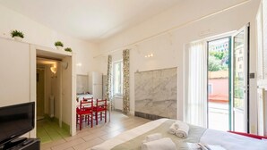 A hotel room with a bed, a TV, a dining area, and a bathroom. - Apartment Vernazzola In Genova, Genova, Italy (Genova)