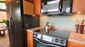 Una cocina con armarios de madera, un refrigerador negro, un microondas y una estufa.