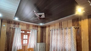 Una habitación de madera con cama, una silla, un armario y un ventilador de techo.