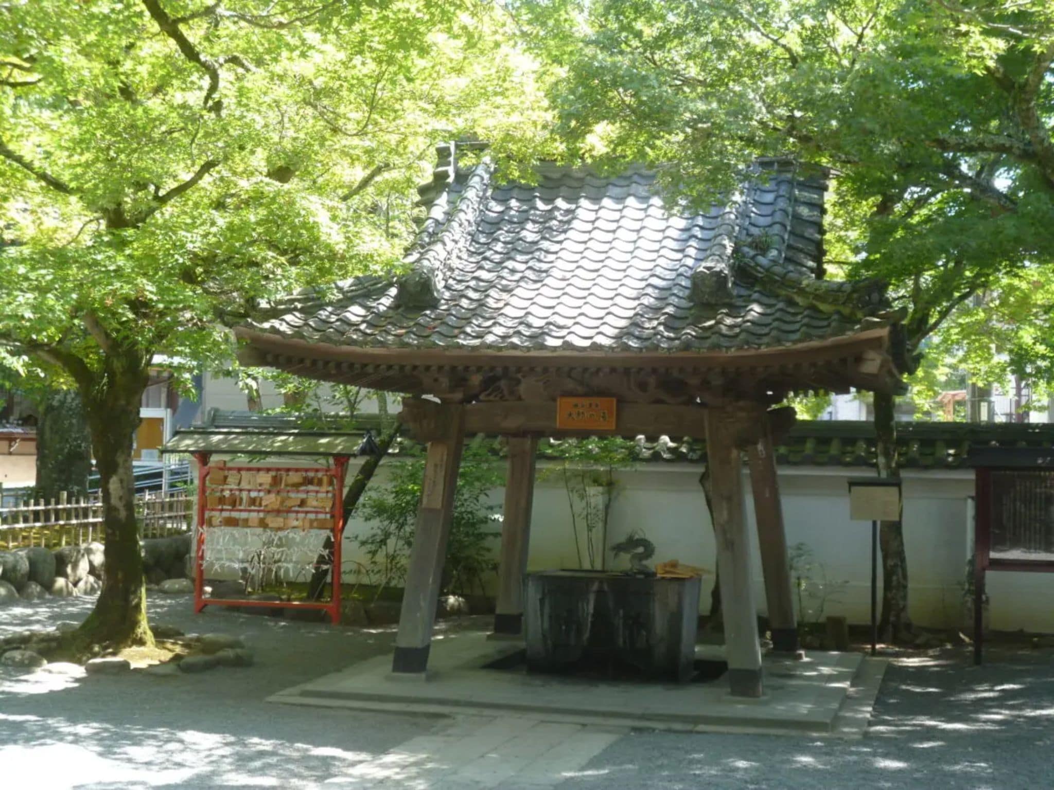 Un pabellón japonés tradicional con techo de tejas, rodeado de árboles.