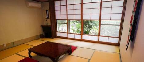 Una habitación japonesa tradicional con suelo de tatami, una mesa de madera baja y paneles shoji.