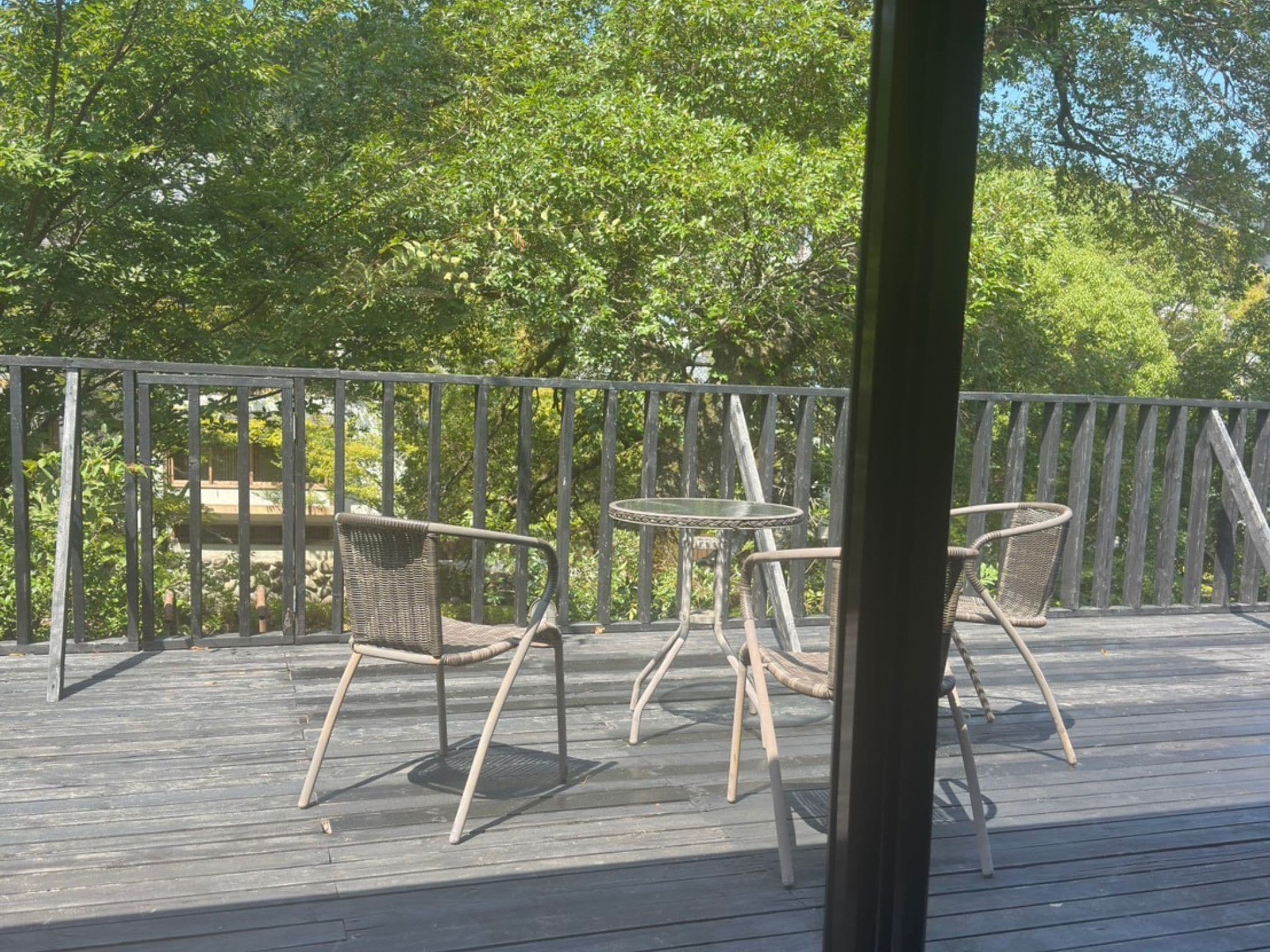 A wooden deck with wicker chairs and a small round table.