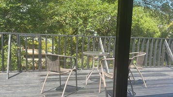 A wooden deck with wicker chairs and a small round table.