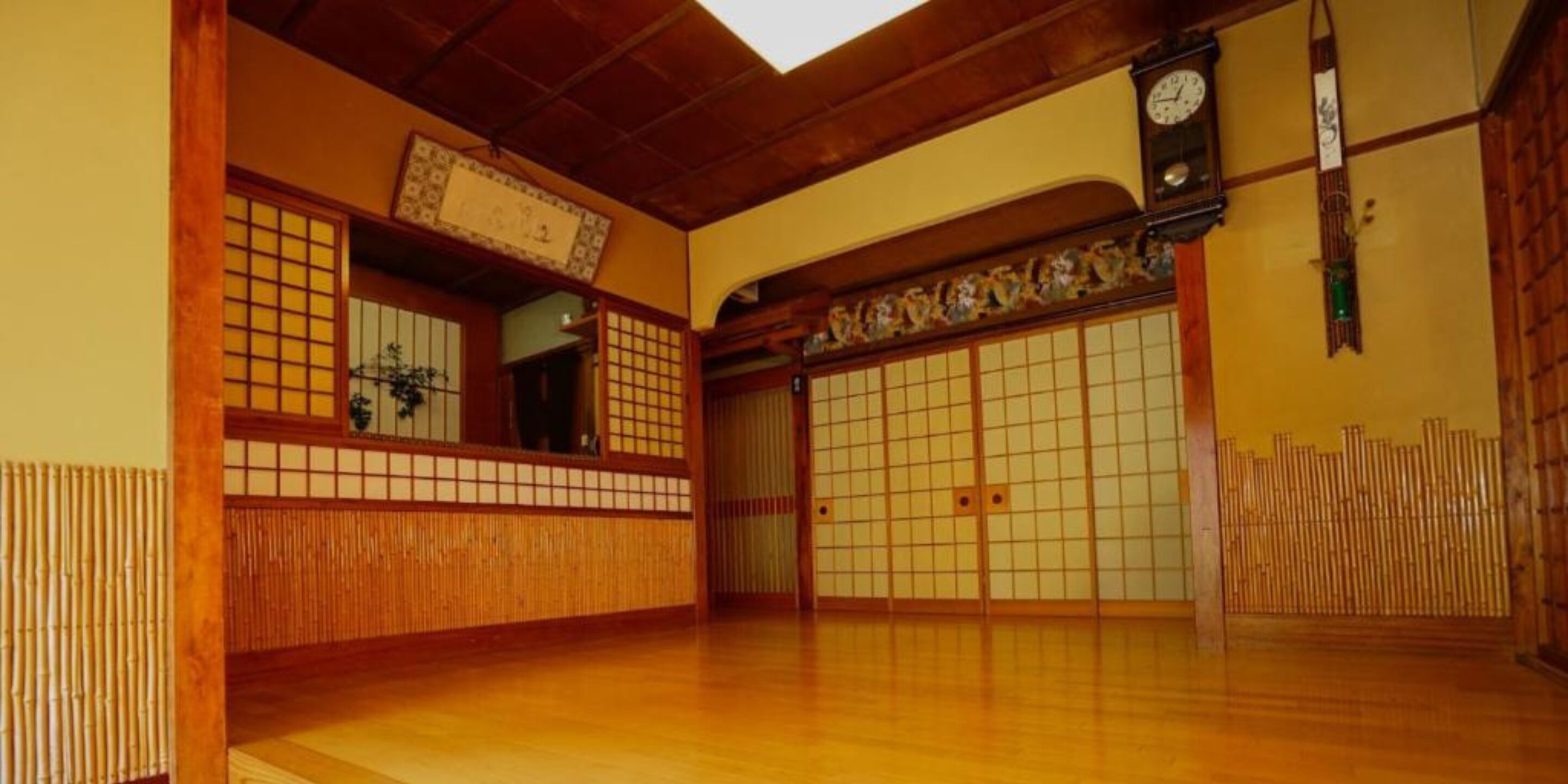 A traditional Japanese room with tatami flooring, sliding doors, and a wooden ceiling.