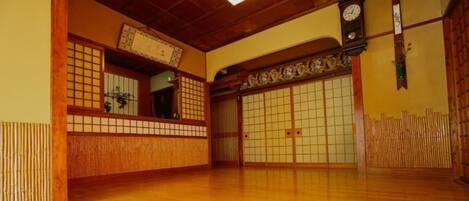A traditional Japanese room with tatami flooring, sliding doors, and a wooden ceiling.
