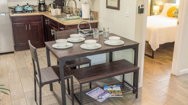 A dining area with a table set for four, a kitchen in the background, and a bedroom visible through an open door. - Quiet Yet Close To Restaurants, Downtown, Coronado (San Diego)