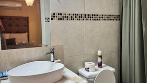 Un baño con un lavamanos ovalado grande, un inodoro y una cortina de ducha.