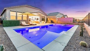 A modern house with a swimming pool, outdoor seating, and a patio area.