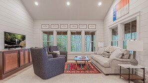 A spacious living room with a fireplace, large windows, and a television.