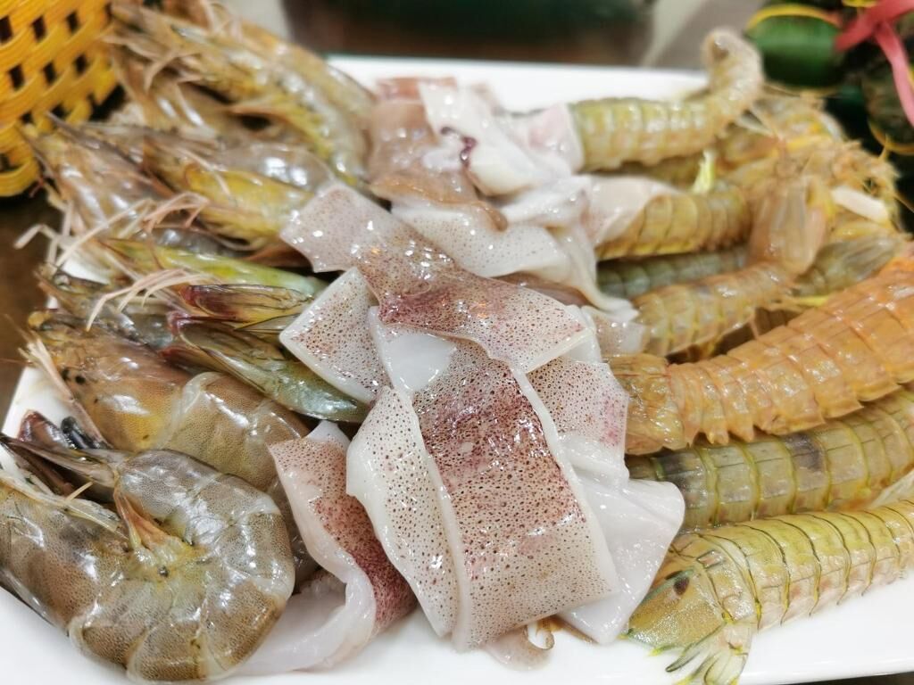 A plate of raw seafood including shrimp and squid.