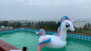 A swimming pool with a large inflatable unicorn float. - Aqua Resort Hai Tien - by BAYLUXURY (Hoang Tien)