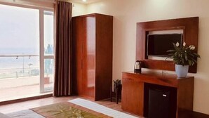 A modern living room with a large window, a wooden entertainment unit, and a potted plant. - Aqua Resort Hai Tien - by BAYLUXURY (Hoang Tien)