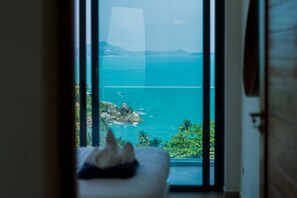 A room with a bed, a view of the ocean, and a window.