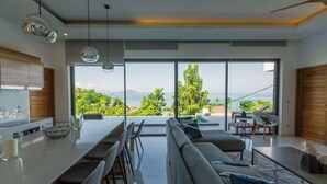 Una cuina moderna amb una illa gran, zona de menjador i vista al mar.