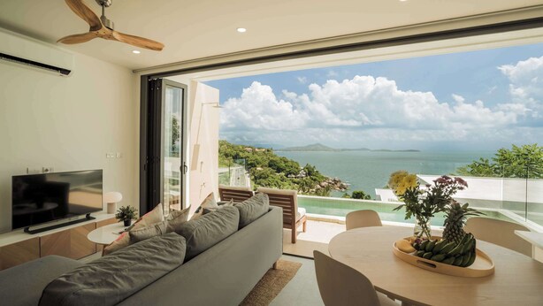 A modern living room with a large TV, comfortable seating, a dining area, and a balcony with a scenic ocean view. - Staylar Seaview Pool Villa - Coral Cove, Koh Samui CC1 (Koh Samui, Coral Cove)