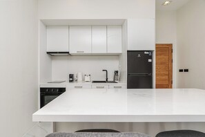 A modern kitchen with white cabinetry, a large island, and a built-in oven.