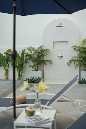 An outdoor seating area with a stone wall, potted plants, and a clear view of the sky.