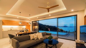 Un salon moderne avec un canapé, une table basse et une vue sur une piscine et des montagnes.