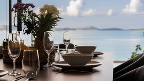 Une table dressée pour le dîner, avec vue sur la mer et les îles lointaines.