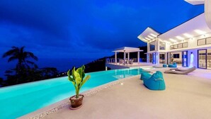 A modern infinity pool with a view of the ocean, a covered outdoor seating area, and a large house with multiple windows. - Staylar Luxury Seaview Pool Villa Maeva, Koh Samui (Koh Samui, Chaweng Noi)