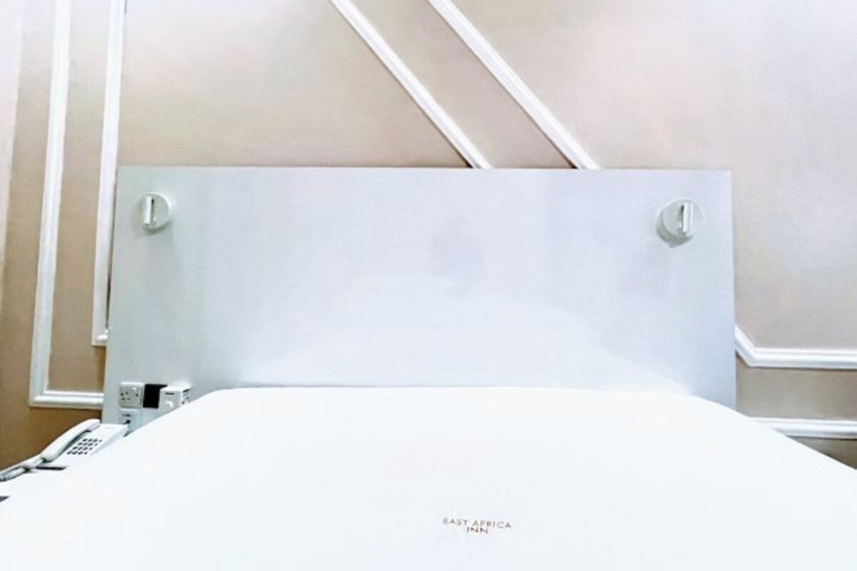 Una habitación de hotel con una cama grande, un teléfono en la mesita de noche y un panel de control en la pared.