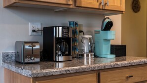 Et køkken med en brødrister, kaffemaskine, blender og elkedel på en granitbordplade.
