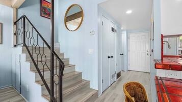 A staircase with a metal railing, a round mirror, and a door with a vent.