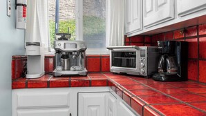 A kitchen with a coffee maker, a toaster, and a kettle on a red-tiled countertop. - 1950's Beachfront Home - Stunning Views! (Aptos)
