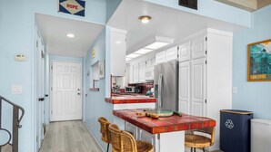 A compact kitchen with a central island, white cabinetry, and a stainless steel refrigerator. - 1950's Beachfront Home - Stunning Views! (Aptos)