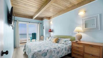 Une chambre à coucher avec un lit, une commode, un miroir et une vue sur la plage.