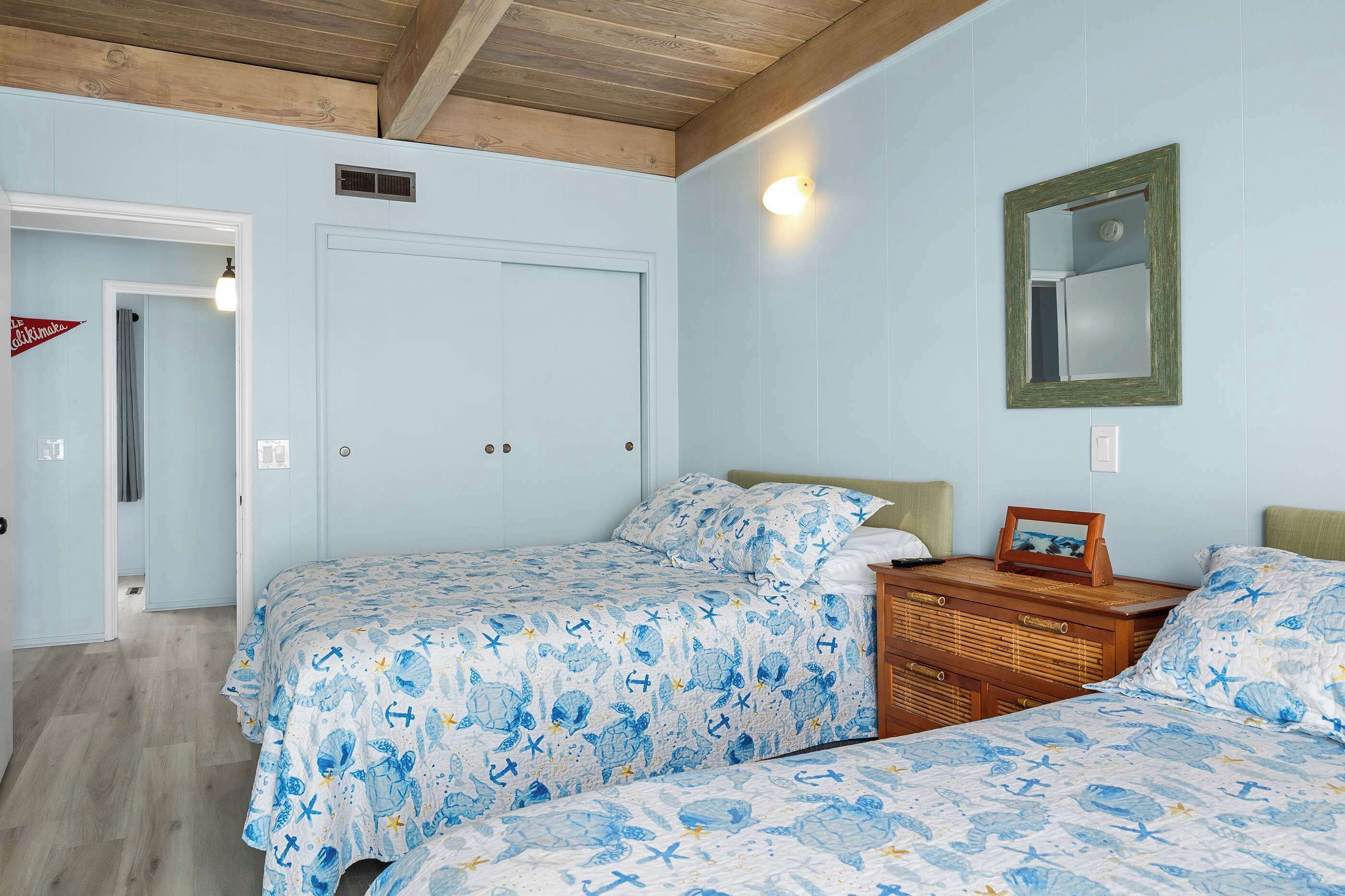 Un dormitorio con dos camas, un aparador, un espejo y una puerta que da a otra habitación.