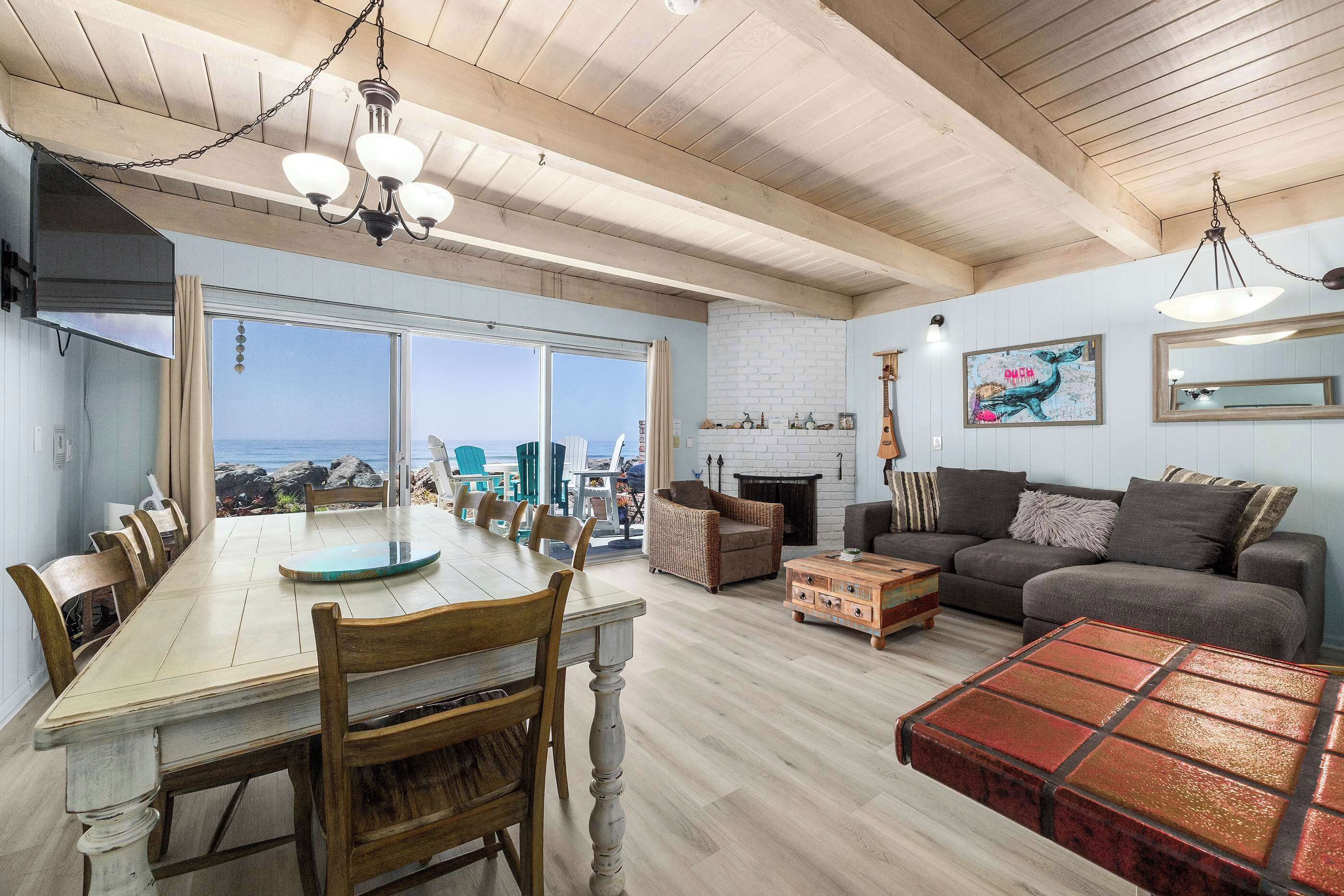 A spacious living area with a dining table, seating, a fireplace, and a view of the ocean.