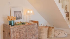 Une pièce chaleureuse avec une commode en bois, un tableau encadré, une lampe et des paniers en osier.