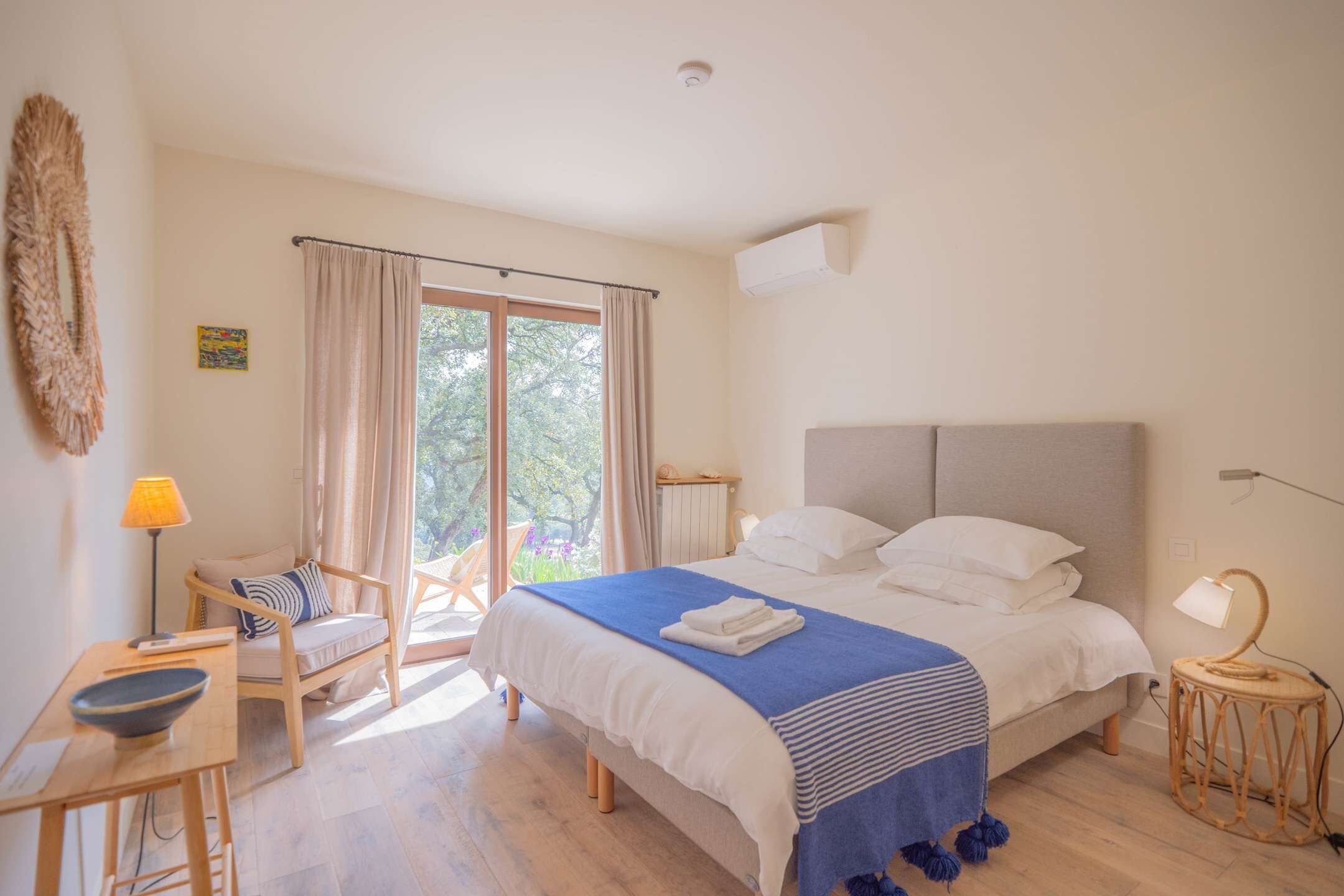 Un dormitorio con una cama grande, una silla, una mesa y vistas al exterior.