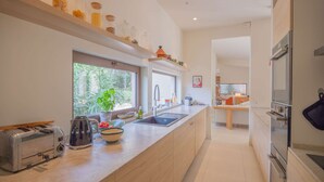 A modern kitchen with a large island, built-in oven, and a window with a view of greenery.