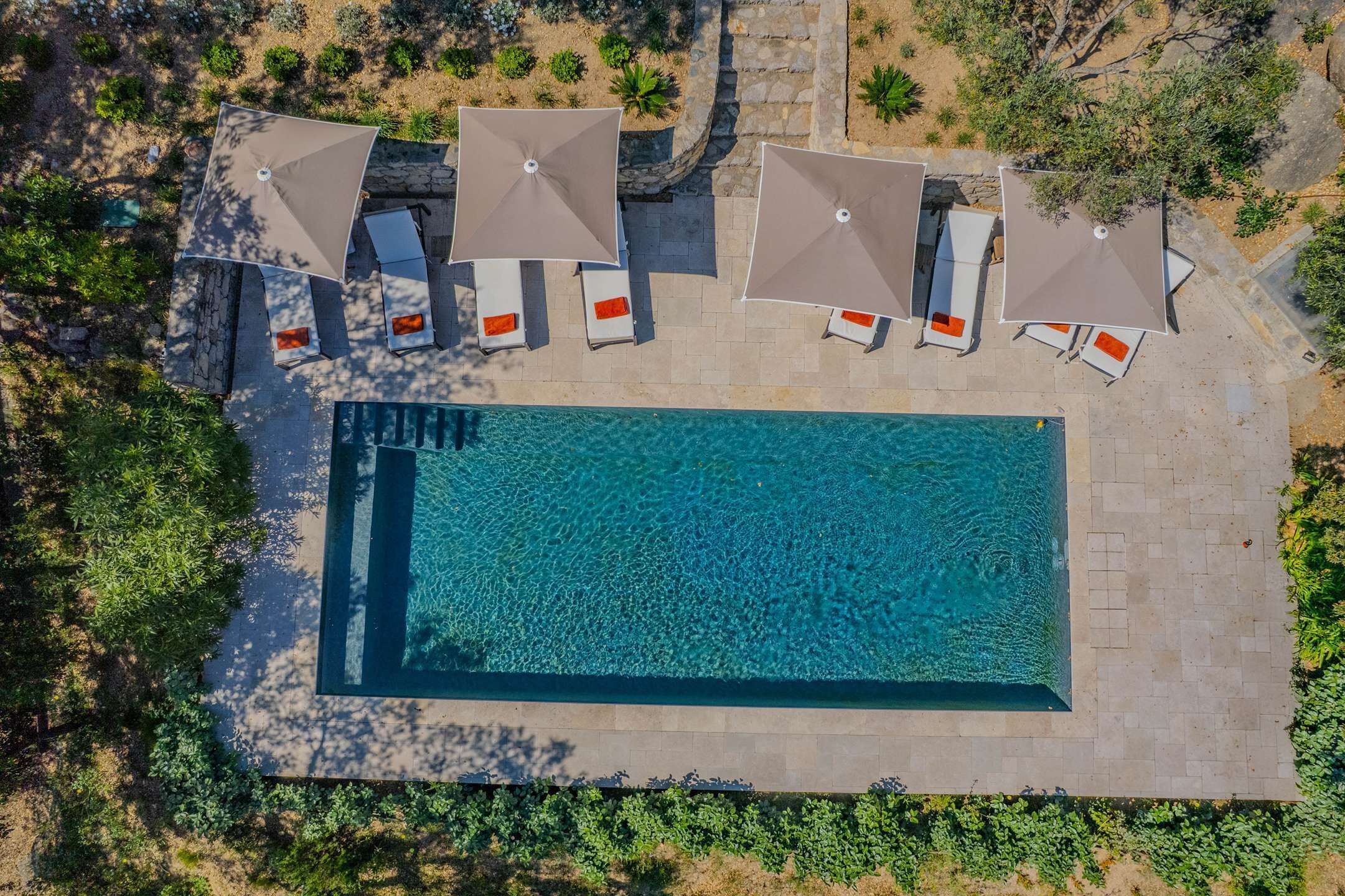 Vista aérea de uma piscina com espreguiçadeiras e guarda-sóis.