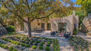 A modern house with a patio area, outdoor seating, and a garden.